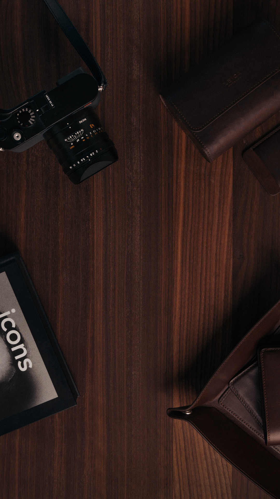 A Leica camera, leather folios and a volume of icons arranged on dark walnut — the desk of the MenWith archive